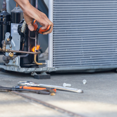 person using a torch ot repair a ac unit