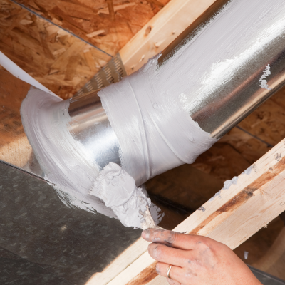 person using paint on an air duct to seal it