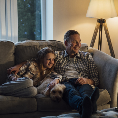 dad and daughter watching a movie together on the sofa