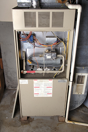 Old-technology, natural-gas furnace in a typical basement installation of a home.