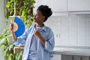 woman fanning herself in hot house
